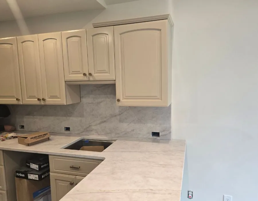 Modern kitchen island with marble countertop and tan cabinets